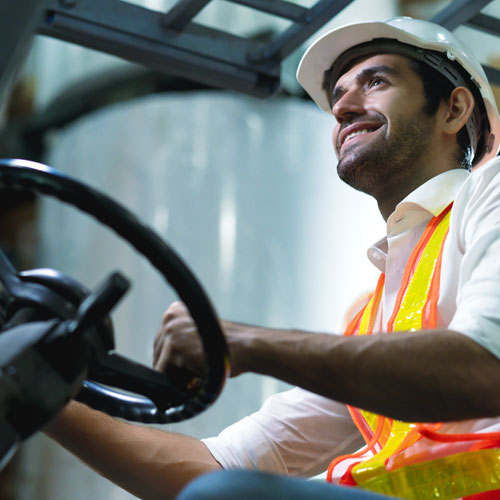 Operario de almacén al lado de una carretilla posando