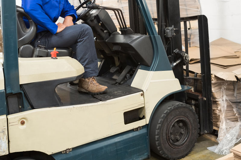 Operario carretillero en jornada laboral trasladando palets con cartón